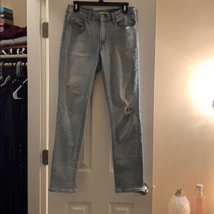 Levi brand jeans, lighter wash, scattered holes